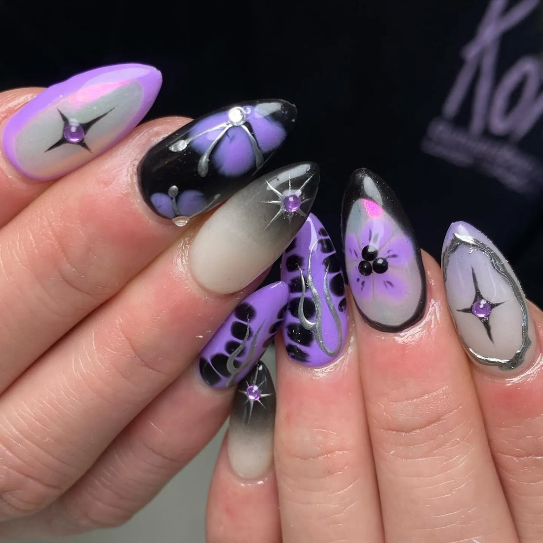 Handmade purple ombre floral press-on nails with chrome star accents and rhinestones.
