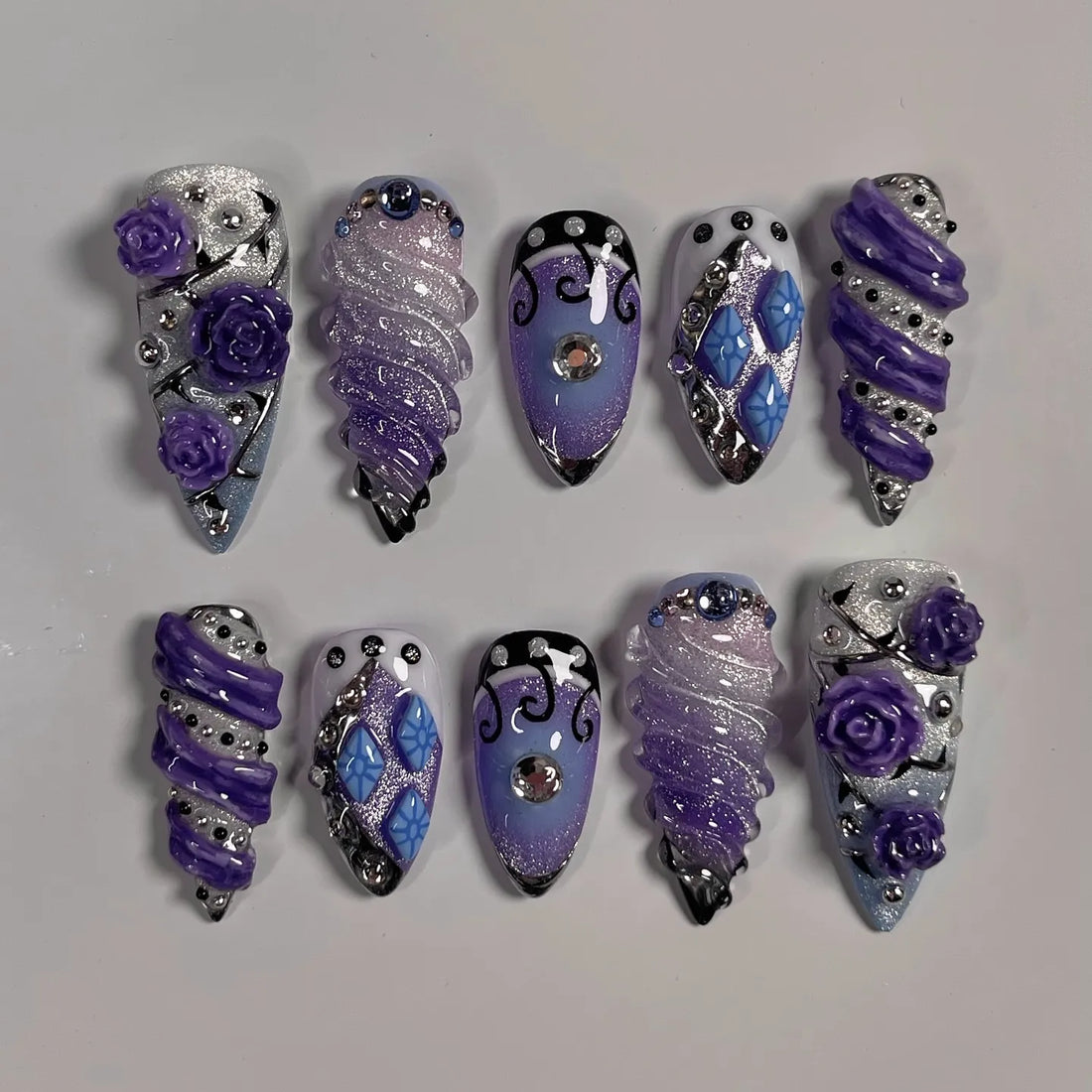 Handmade purple and silver fantasy press-on nails with glitter, roses, and rhinestone accents.