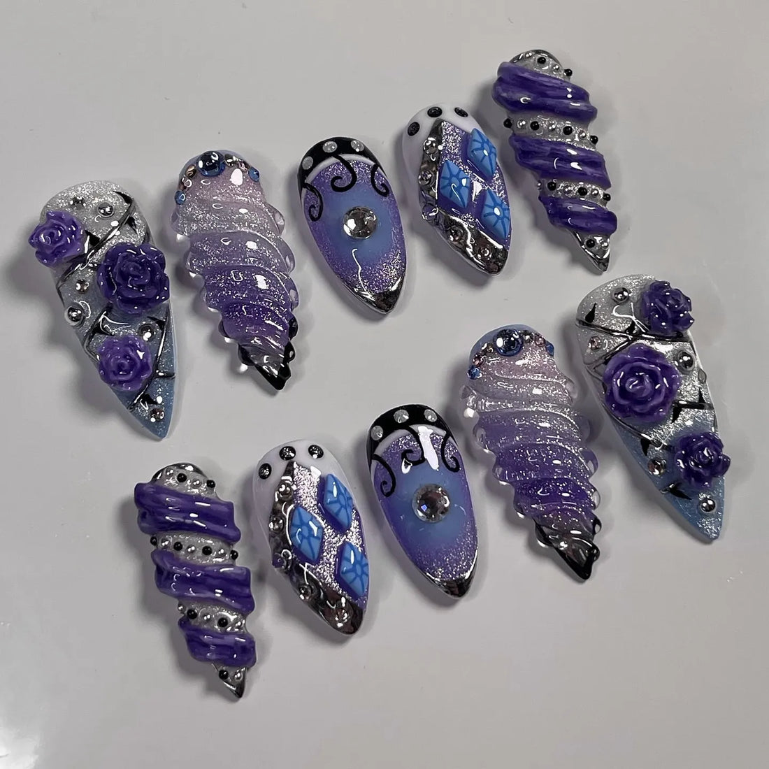 Handmade purple and silver fantasy press-on nails with glitter, roses, and rhinestone accents.