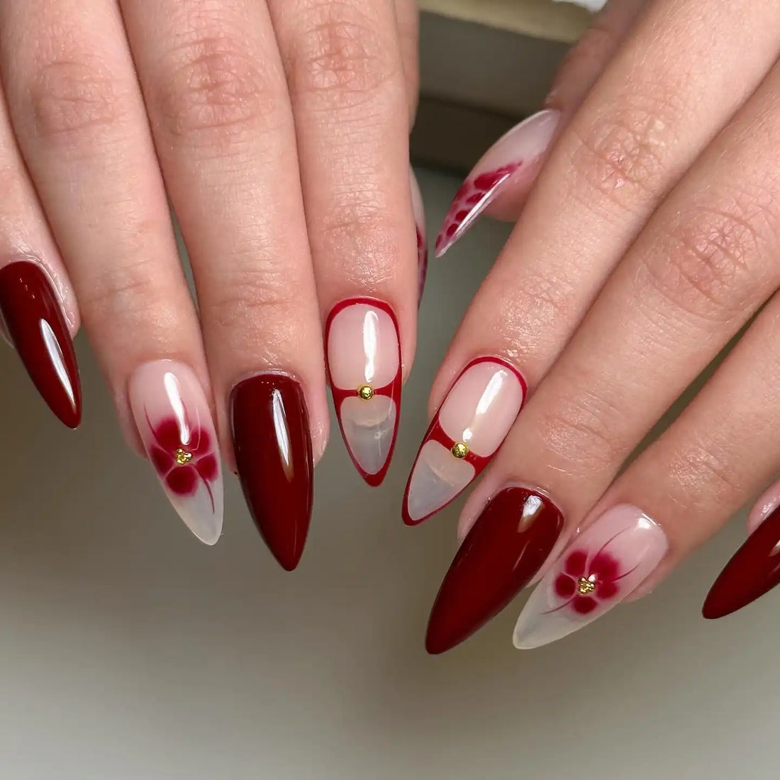 Hand with handmade red blossom and snakeskin design press-on nails, stiletto-shaped