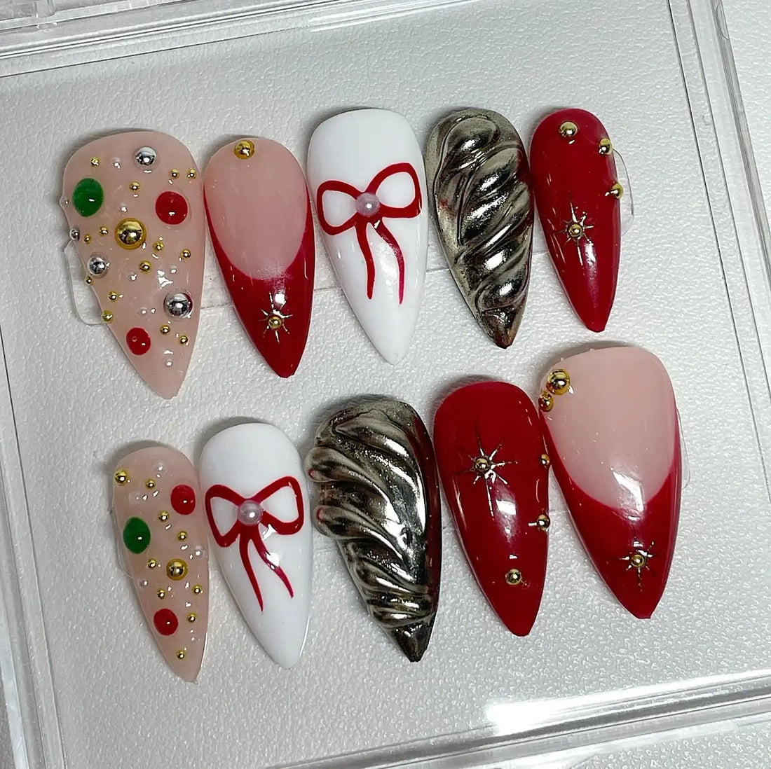 Handmade Christmas press-on nails with red bows, chrome stars, and festive decorations.