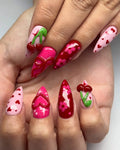 Handmade press-on nails with 3D cherry, heart, bow, and floral designs in pink and red.