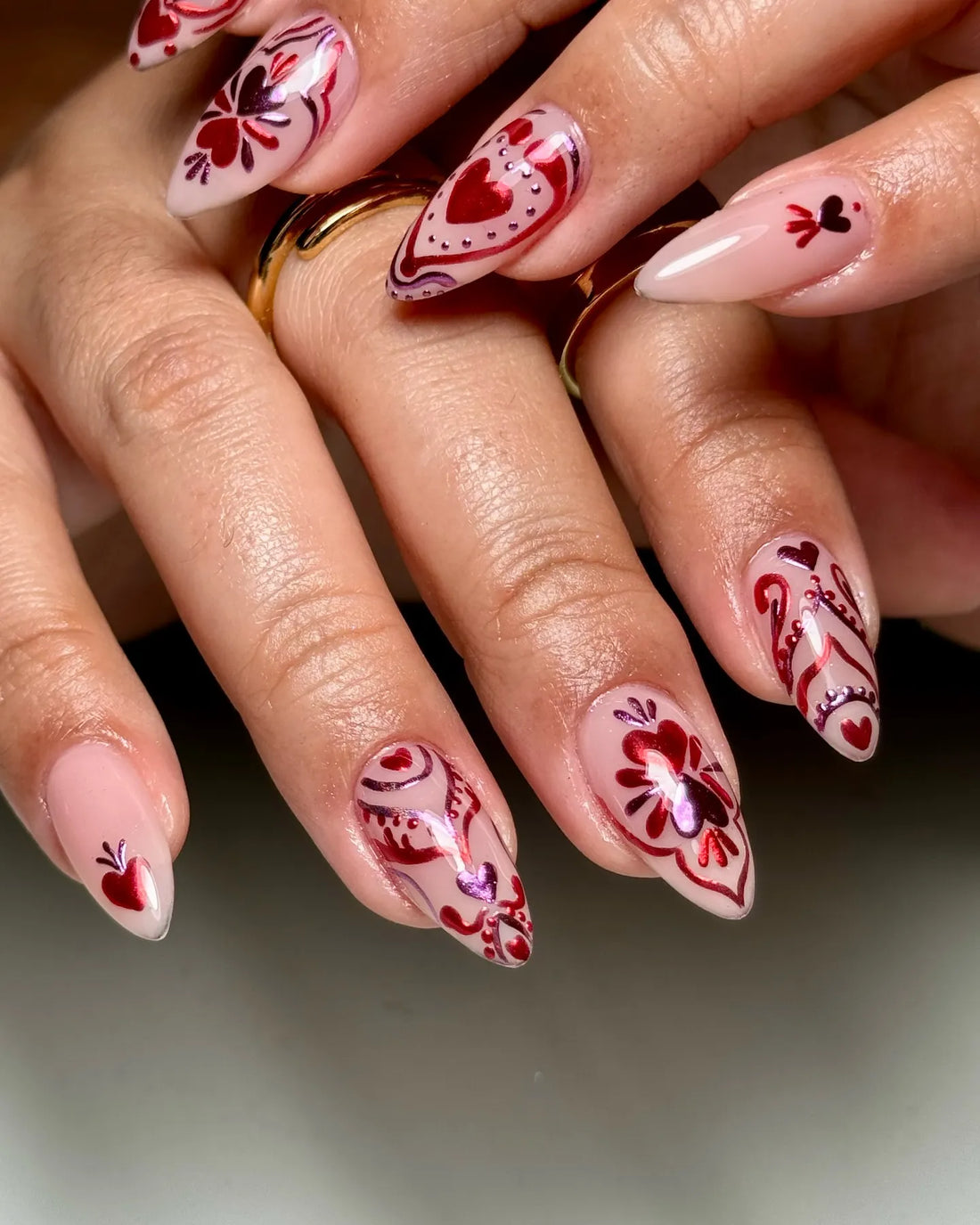 Handmade press-on nails with red and pink heart and floral designs on nude base