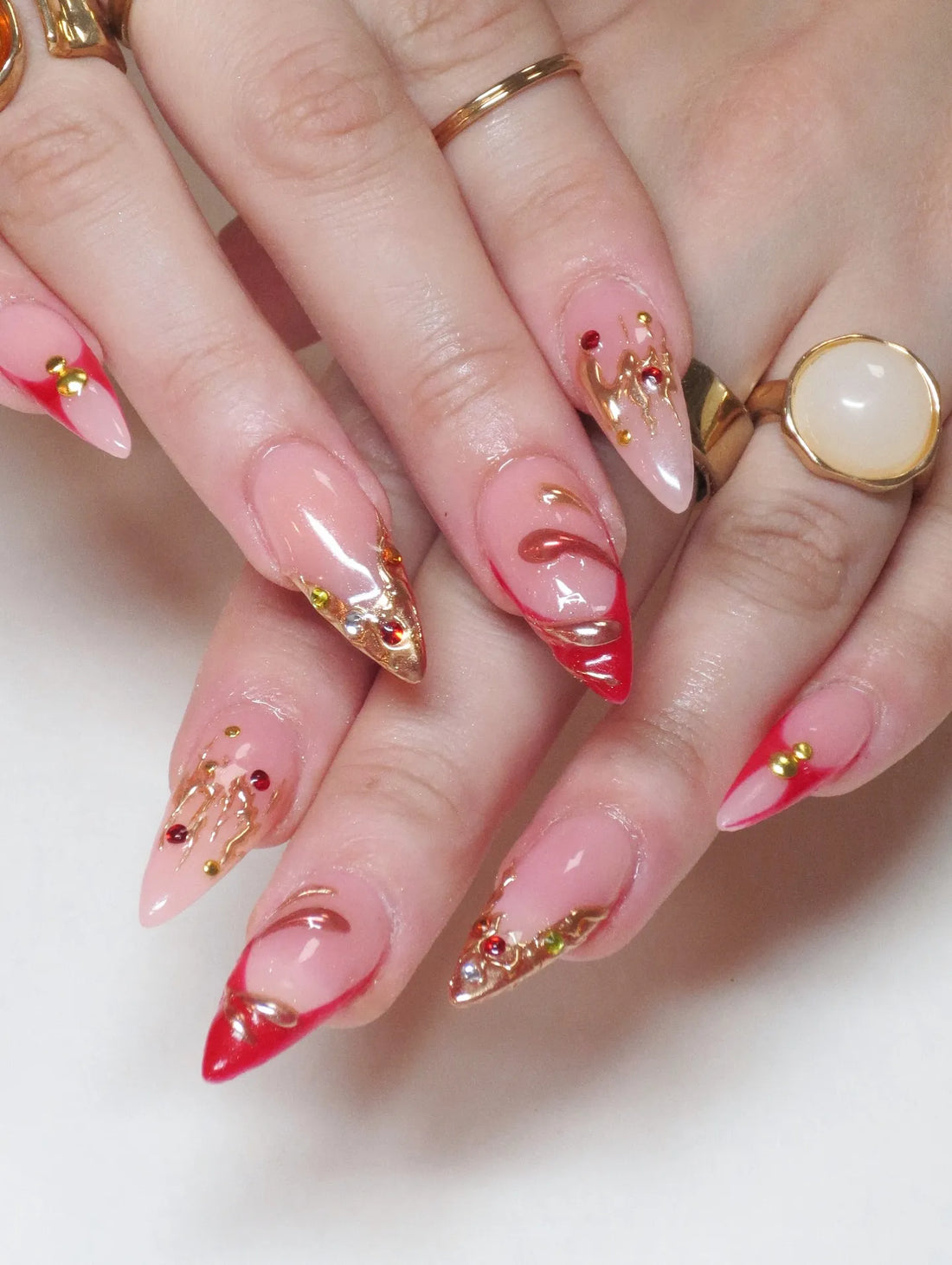 Handmade red French tip press-on nails with gold chrome drip and rhinestone accents