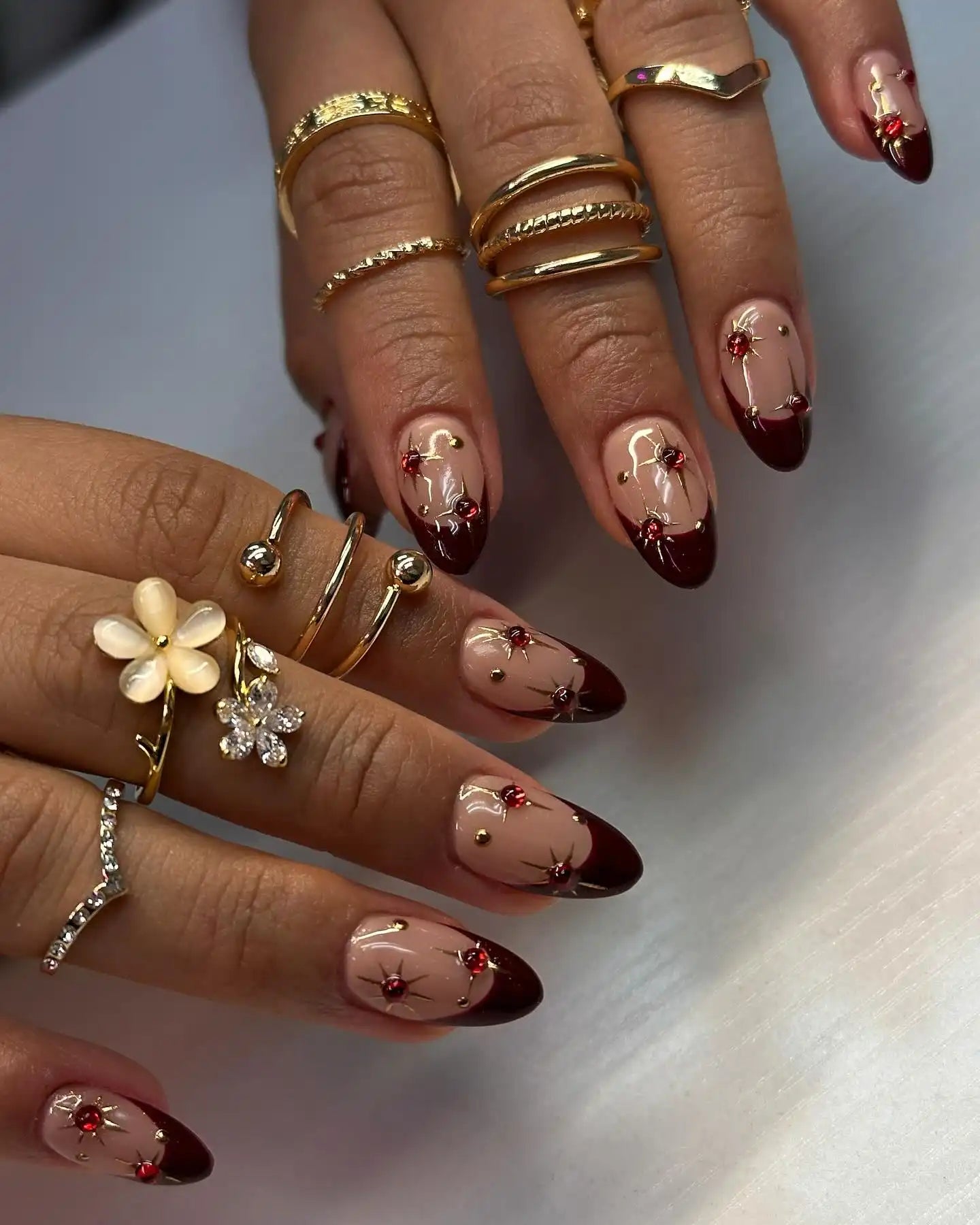 Handmade press-on nails with wine red tips, gold star designs, and red gem accents