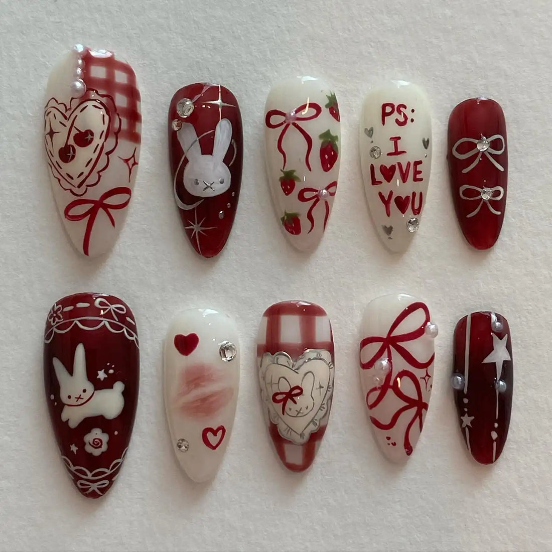 Handmade red gingham press-on nails with bunny, heart, strawberry, bow, and love letter designs