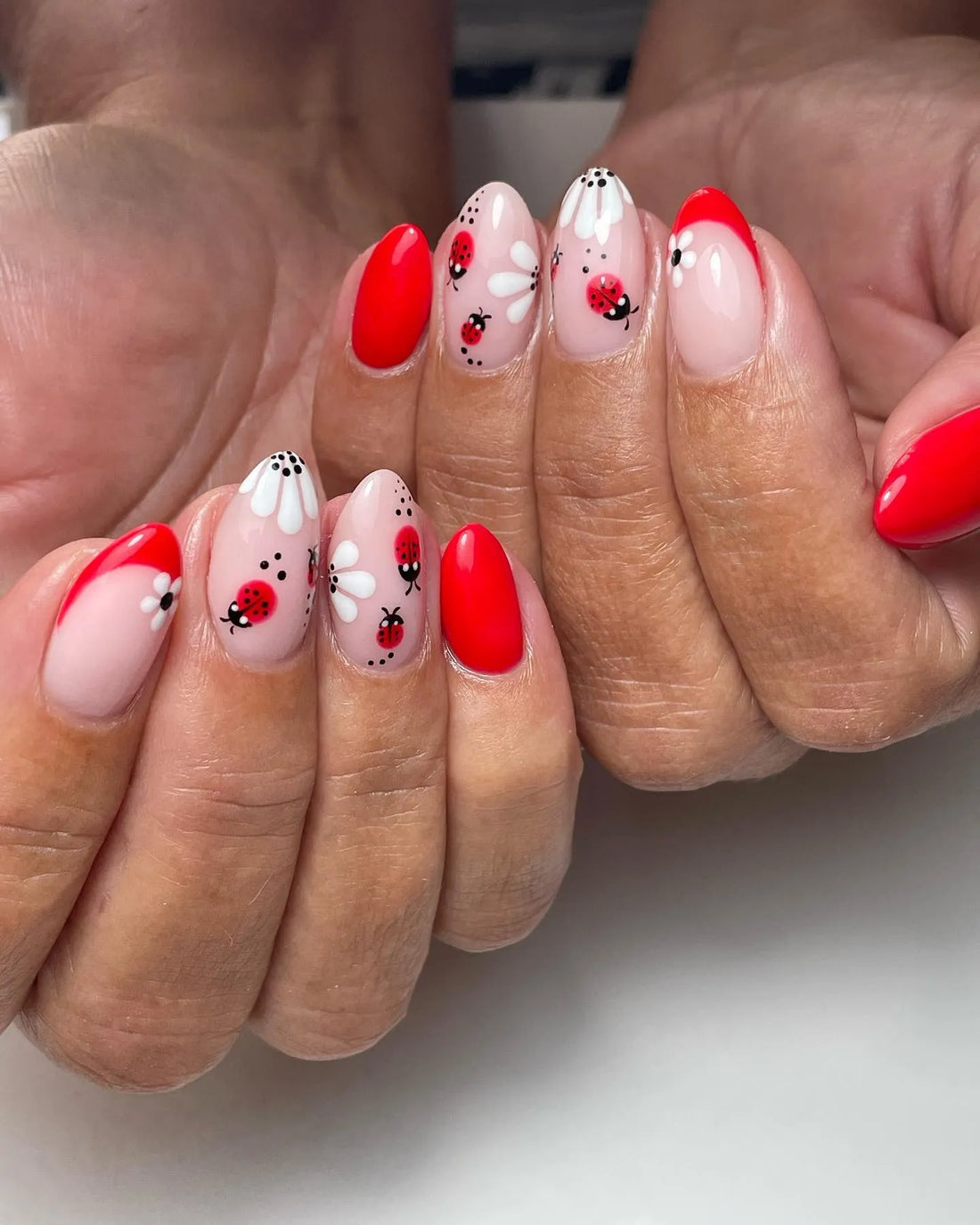 Handmade press-on nails with red ladybug and white daisy floral French tip designs