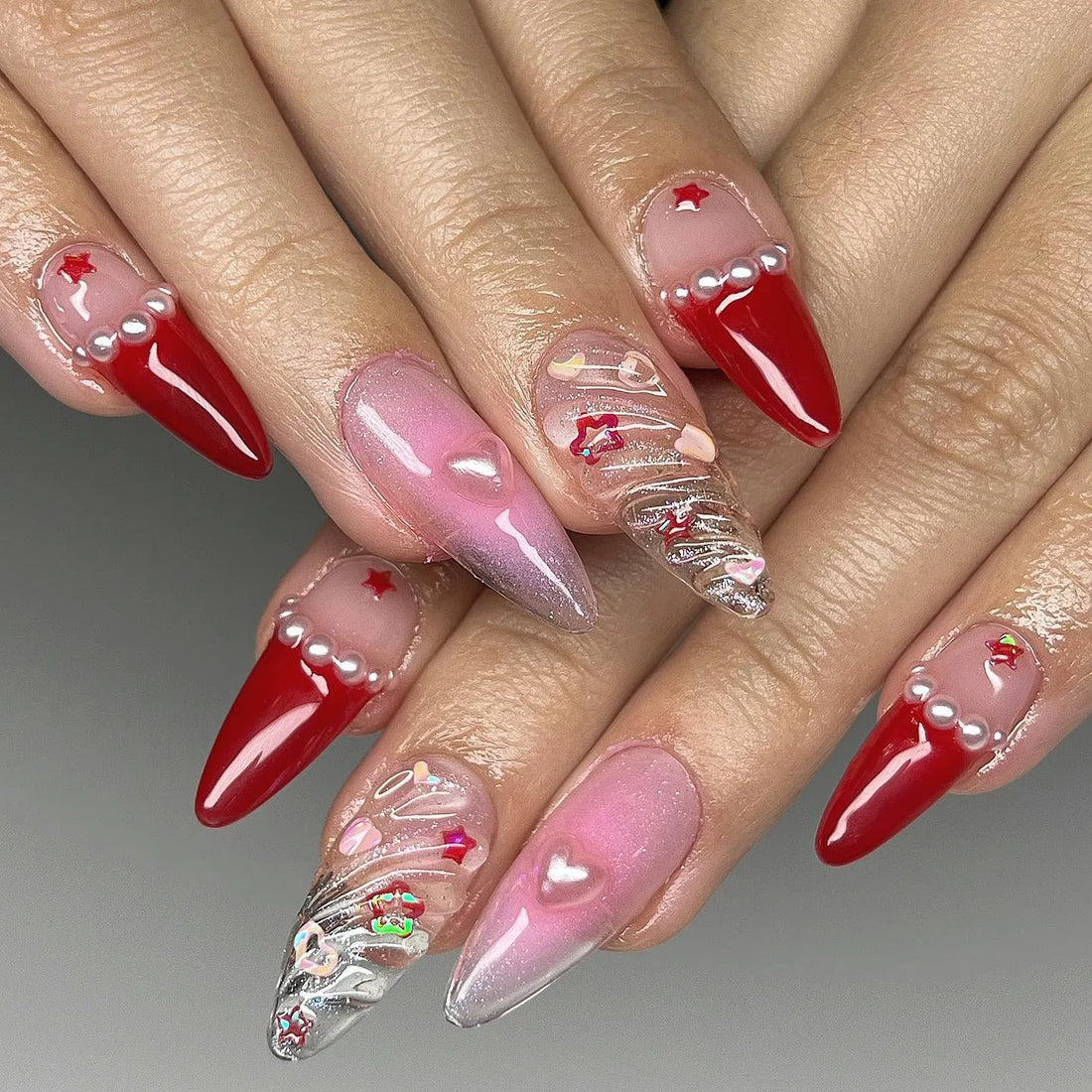 Handmade long press-on nails with red tips, pearls, hearts, stars, and clear festive accents.