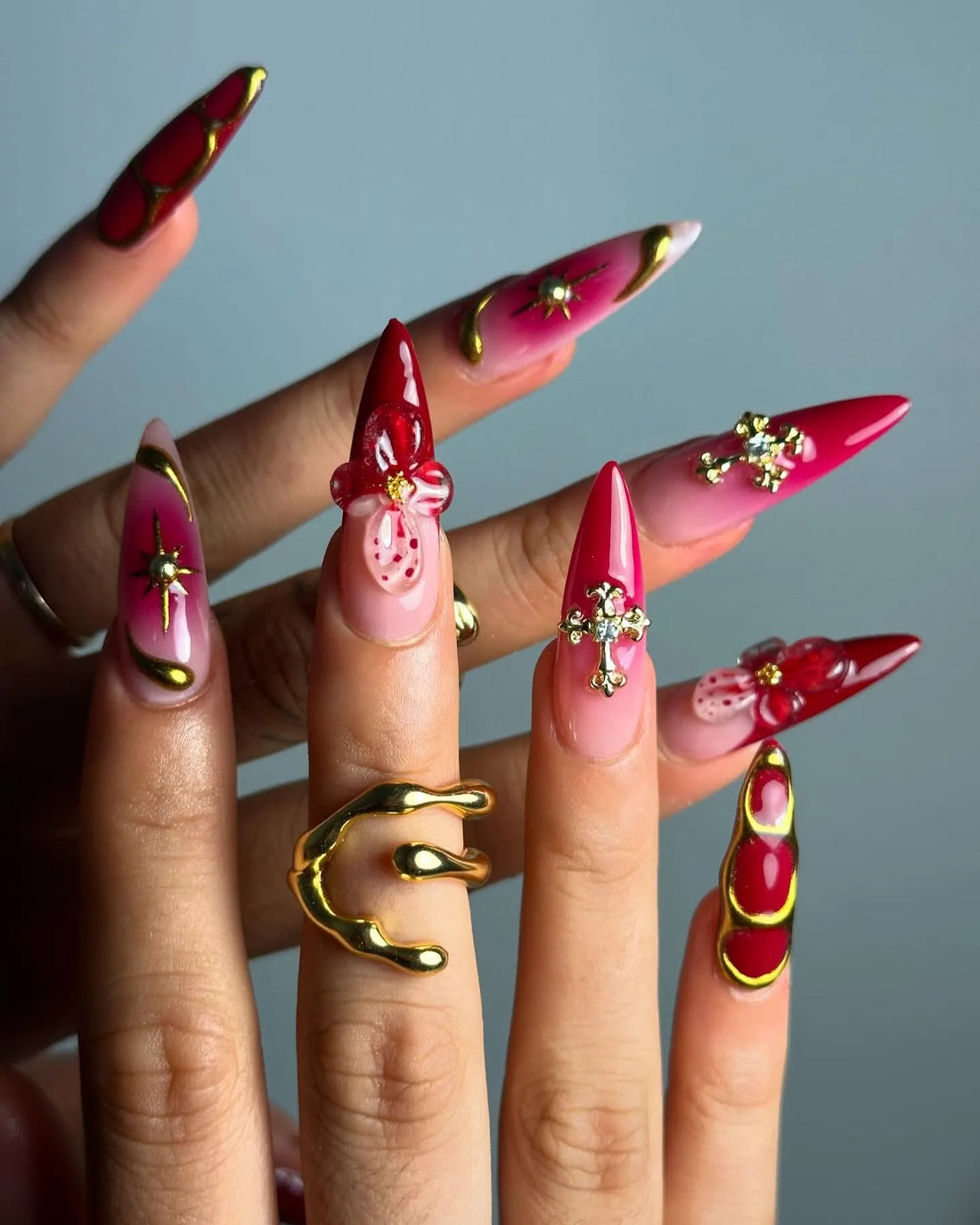 Handmade red and pink press-on nails with 3D floral, cross, celestial gold accents, almond shape
