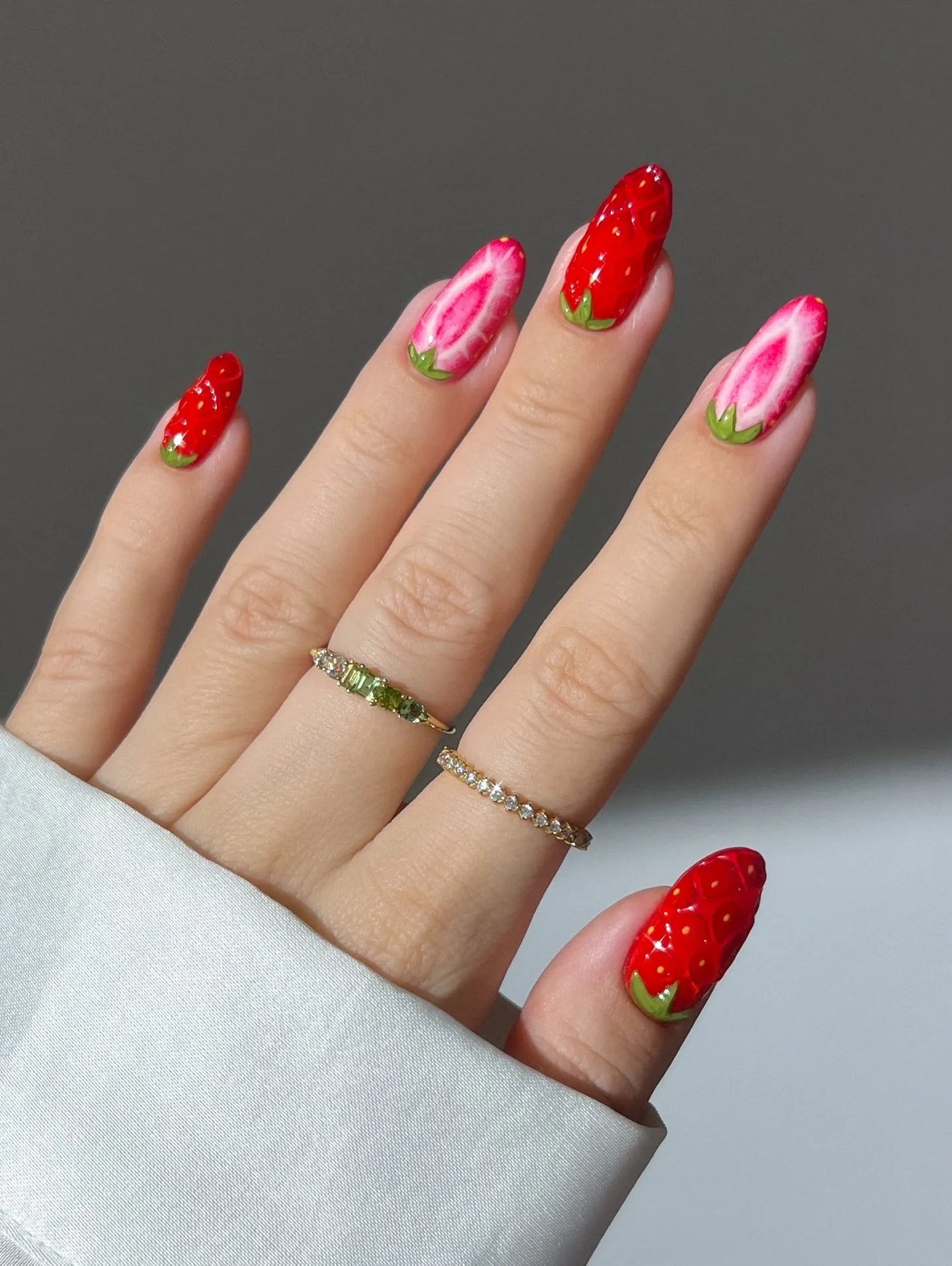 Hand with handmade strawberry fruit design summer press-on nails, red and pink kawaii style.