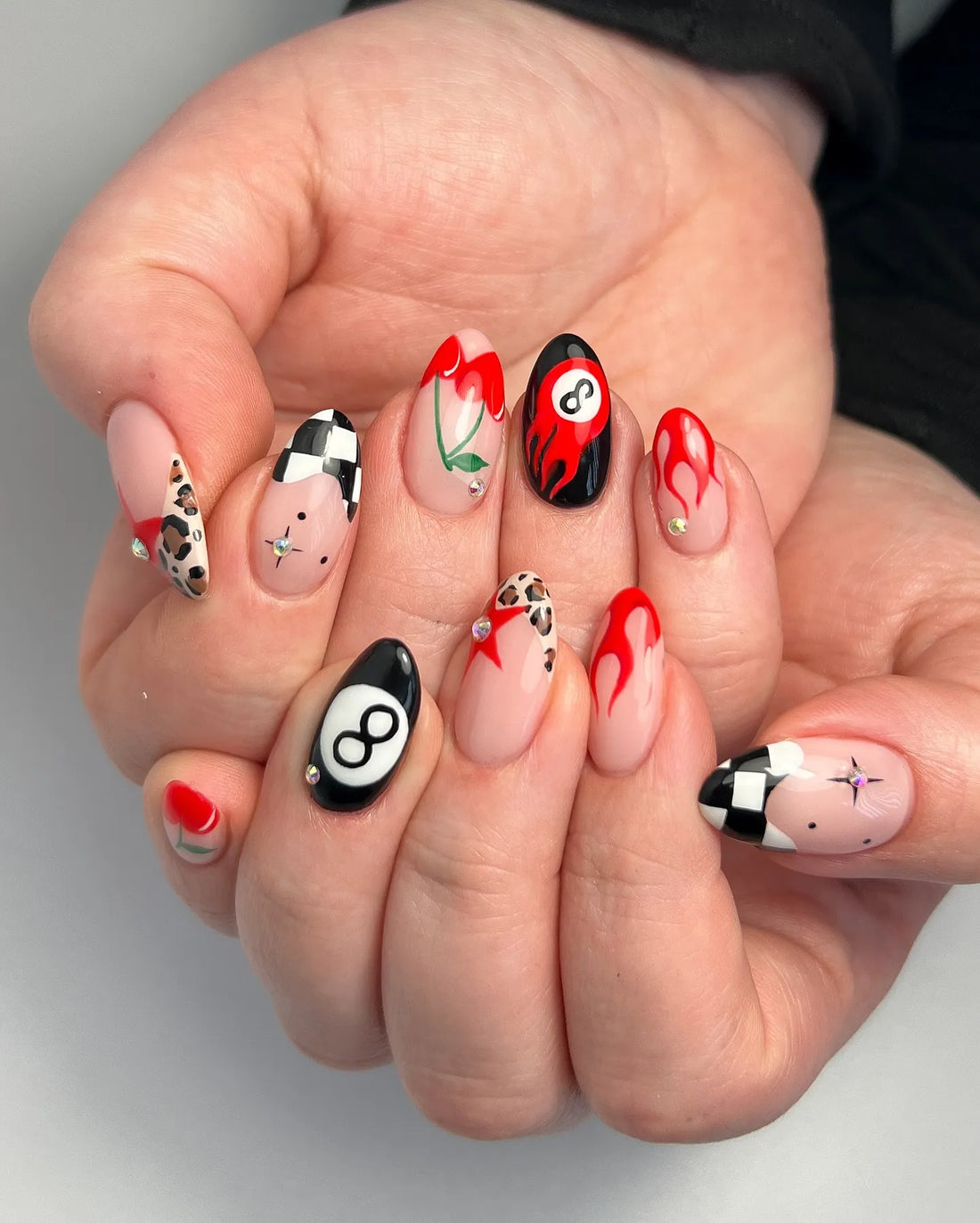Handmade press-on nails with red flames, cherries, black eight ball, leopard, and checker patterns.