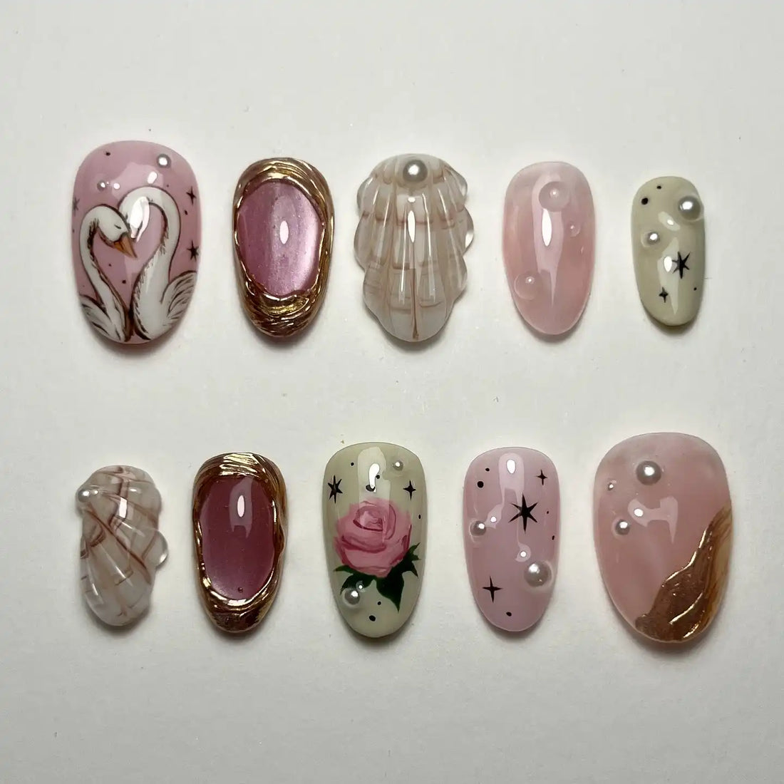 Handmade press-on nails with swan, pink rose, pearl, and gem accents on pastel backgrounds