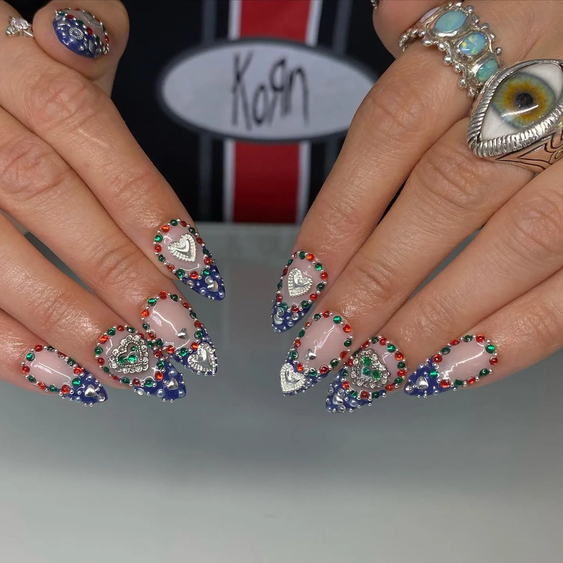 Handmade royal blue ombre heart press-on nails with colorful chrome gemstones.