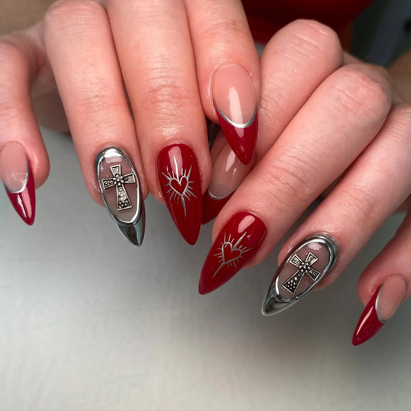 Handmade red and silver press-on nails with cross charms and heart designs, gothic style.