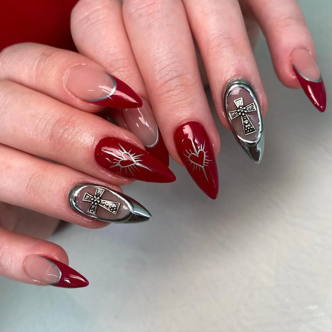 Handmade red and silver press-on nails with cross charms and heart designs, gothic style.