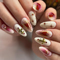 Handmade press-on nails with gold fleur-de-lis, red sacred hearts, and pink accents