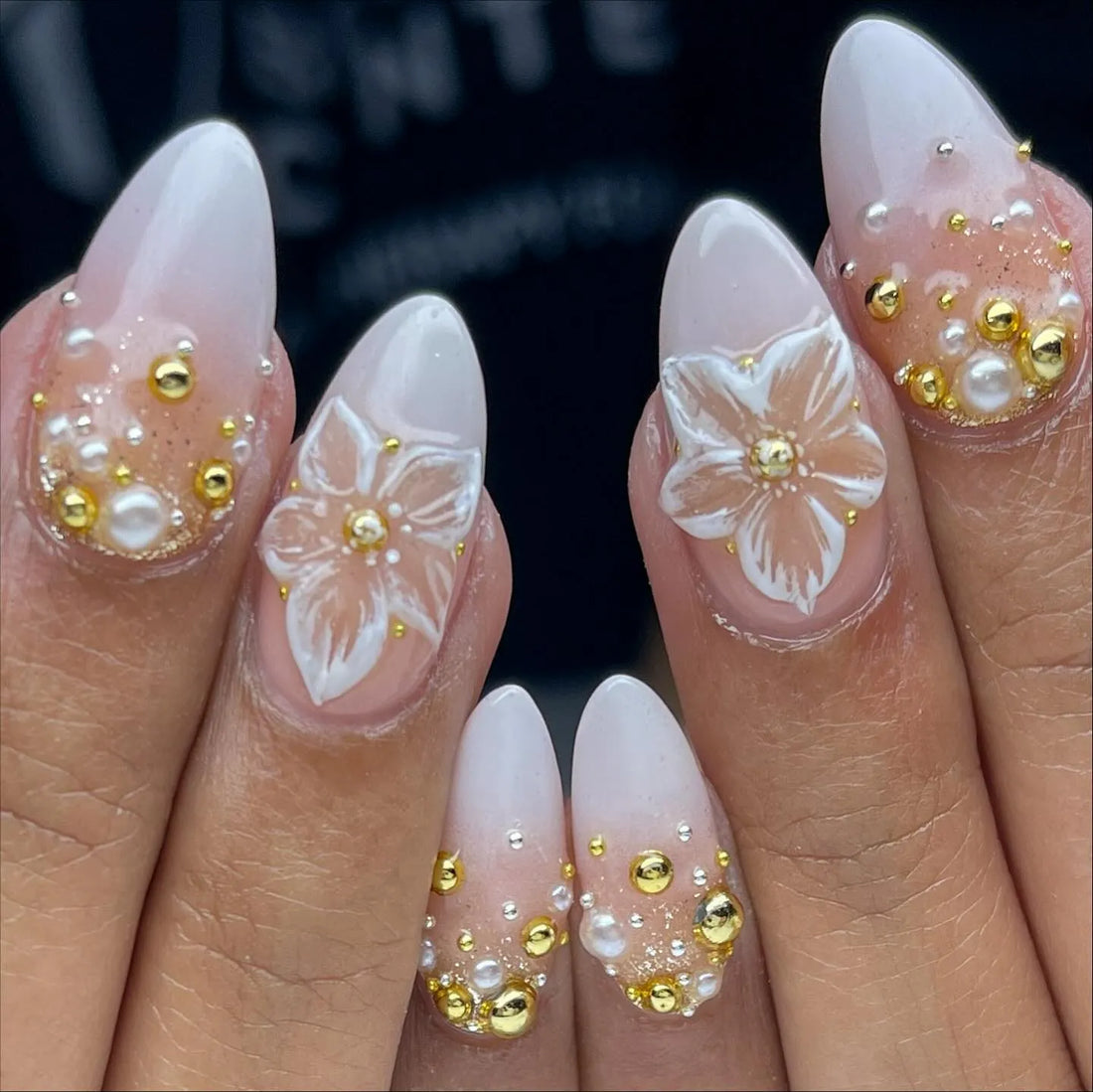 Handmade press-on nails with white floral 3D designs, gold accents, and pearl embellishments.