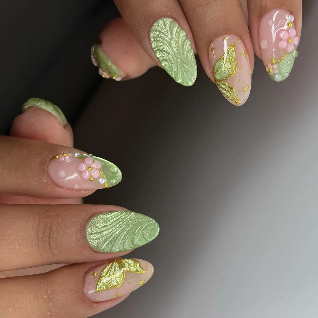 Handmade sage green press-on nails with 3D floral, butterfly, and leaf designs.