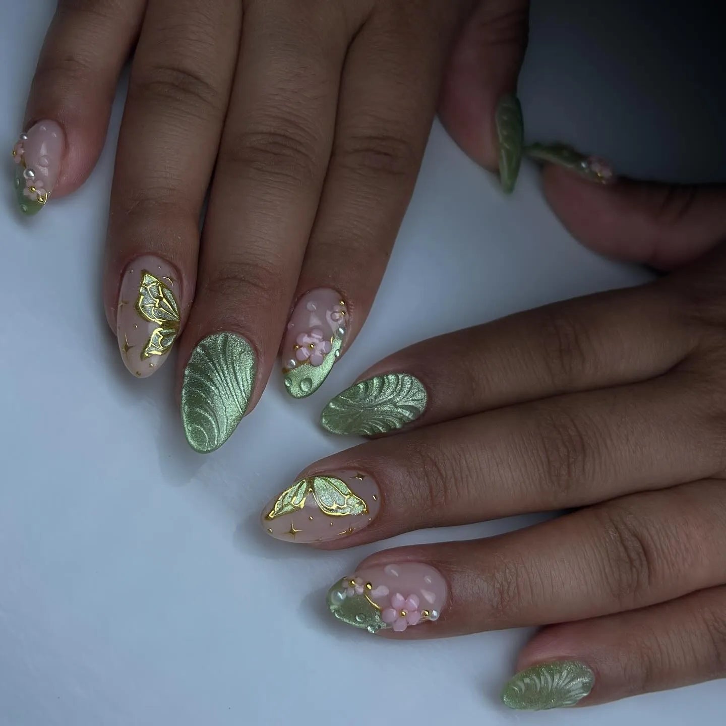 Handmade sage green press-on nails with butterfly, floral, and leaf 3D designs.