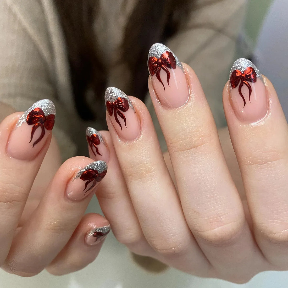 Handmade press-on nails with silver glitter French tips and metallic red ribbon bow designs
