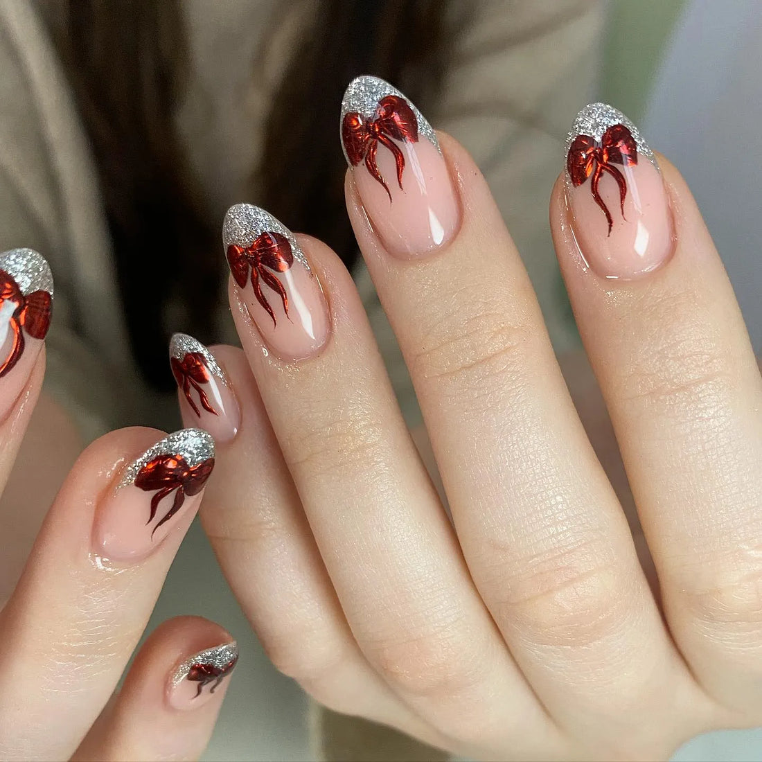 Handmade press-on nails with silver glitter French tips and metallic red ribbon bow designs