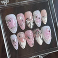 Handmade pink and white press-on nails with silver ribbon, bow, and gem designs