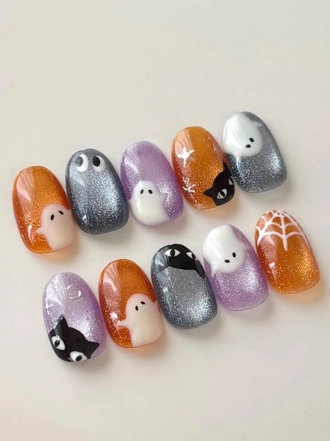 Handmade press-on nails with glittery Halloween ghost, black cat, and spider web designs