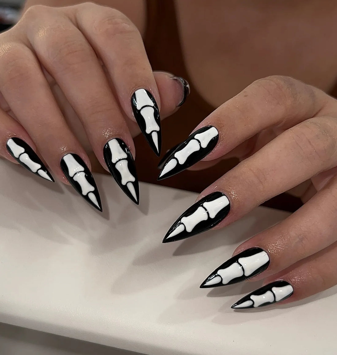 Handmade black stiletto press-on nails with white skeleton bone gothic Halloween design.
