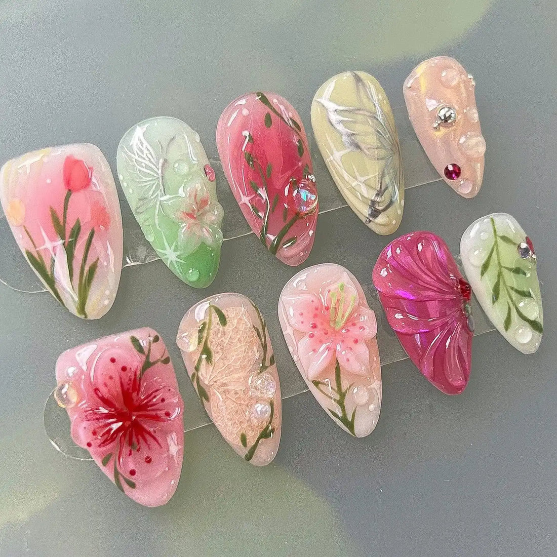 Handmade spring garden floral press-on nails with pink, green, and nature-inspired art designs.