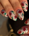 Handmade stained glass press-on nails with red floral and green leaf design, silver outlines.