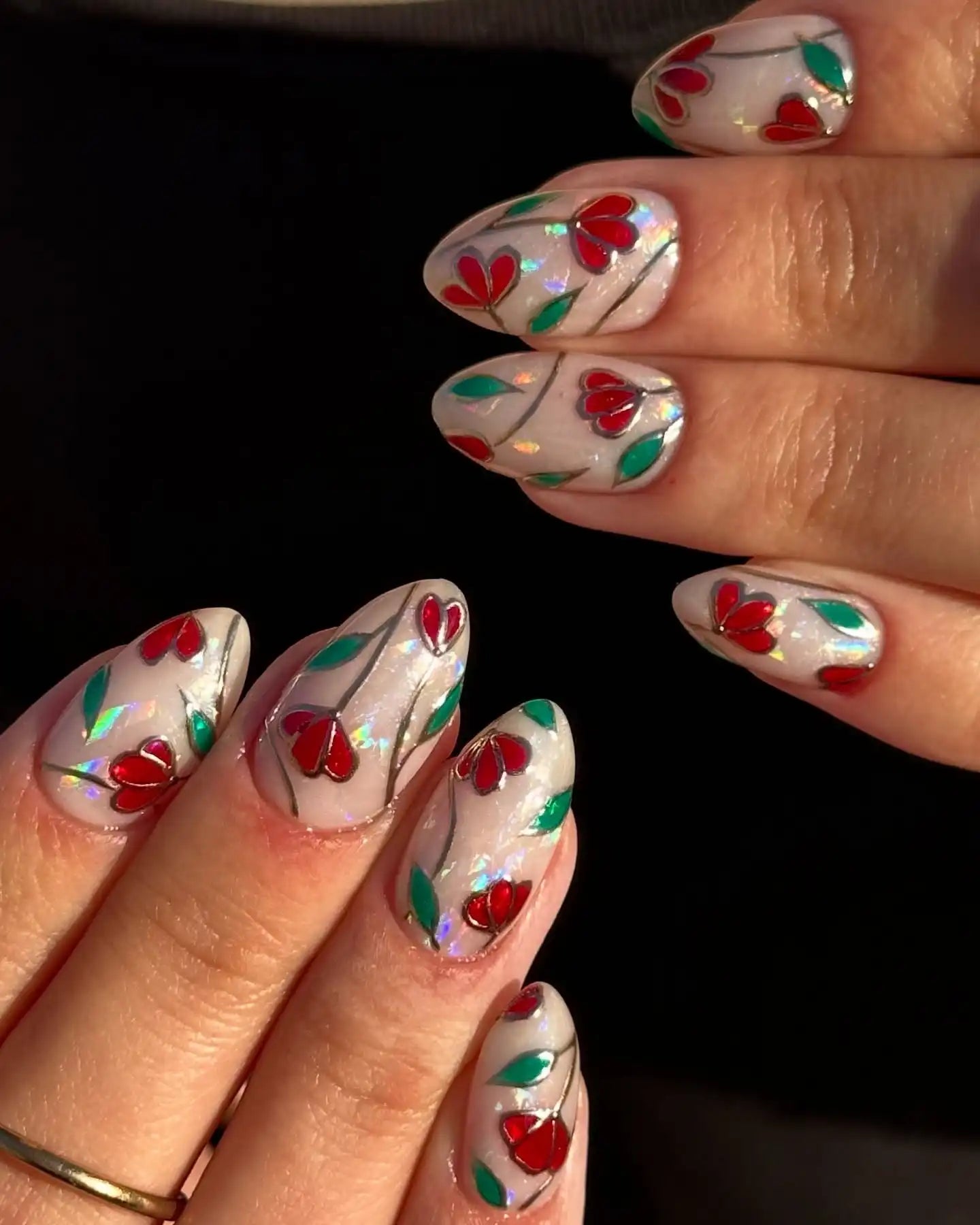 Handmade stained glass press-on nails with red floral and green leaf designs on a silver base