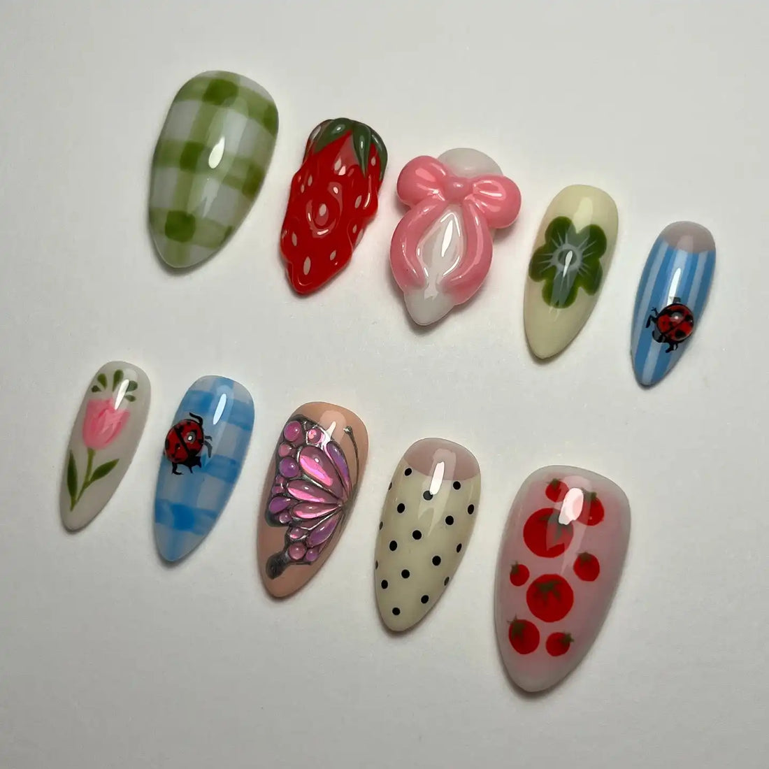 Handmade press-on nails with strawberry, gingham, ladybug, flower, polka dot, and butterfly designs.