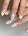 Handmade press-on nails with 3D floral designs, pastel blue, yellow, and white accents
