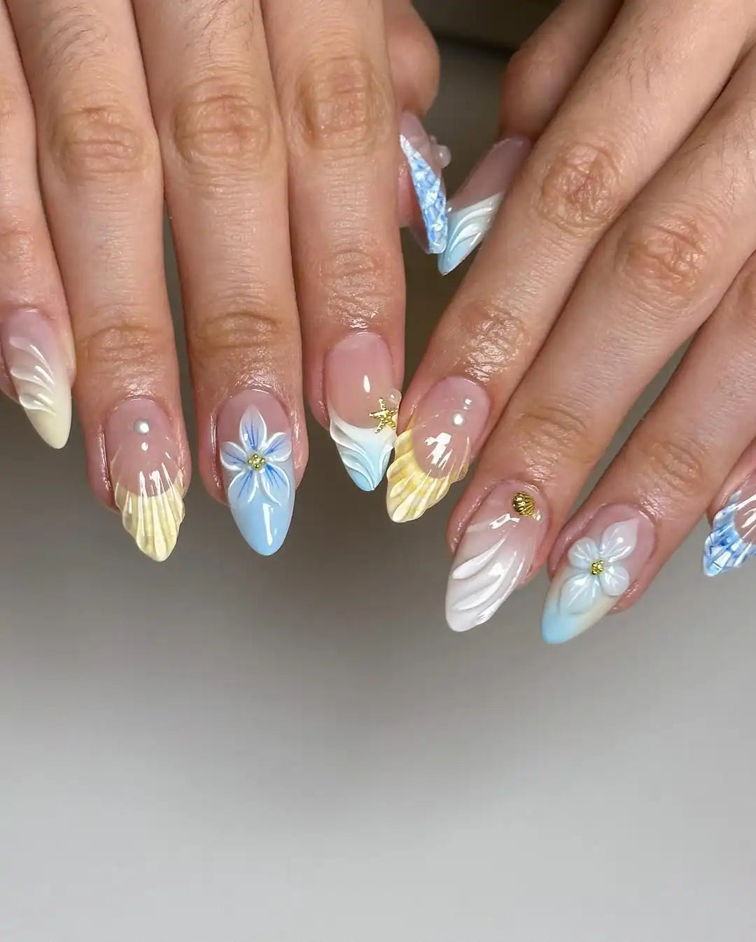 Handmade press-on nails with 3D florals, blue and yellow mermaid-inspired French tips.