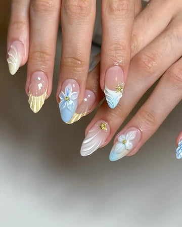 Hand with summer-themed 3D floral mermaid press-on nails in pastel blue, nude and yellow.