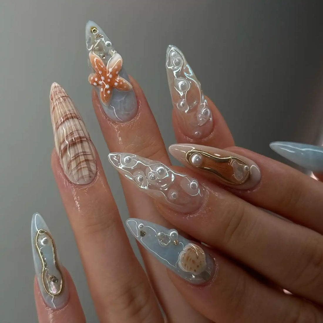 Handmade press-on nails with seashell, starfish, white pearls, and ocean-inspired designs.