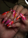 Hand with long press-on nails in pink, orange, and white sunset aura gradient with abstract stars.