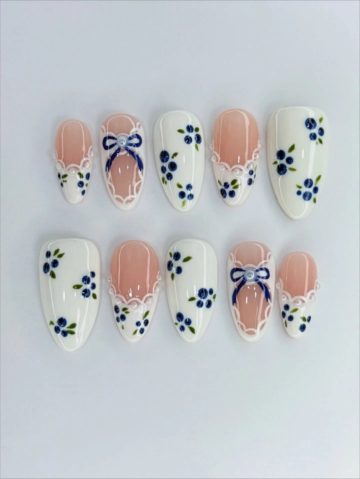 Handmade press-on nails with blue floral and gingham bow designs, lace ribbon accents
