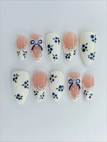 Handmade press-on nails with blue floral and gingham bow designs, lace ribbon accents