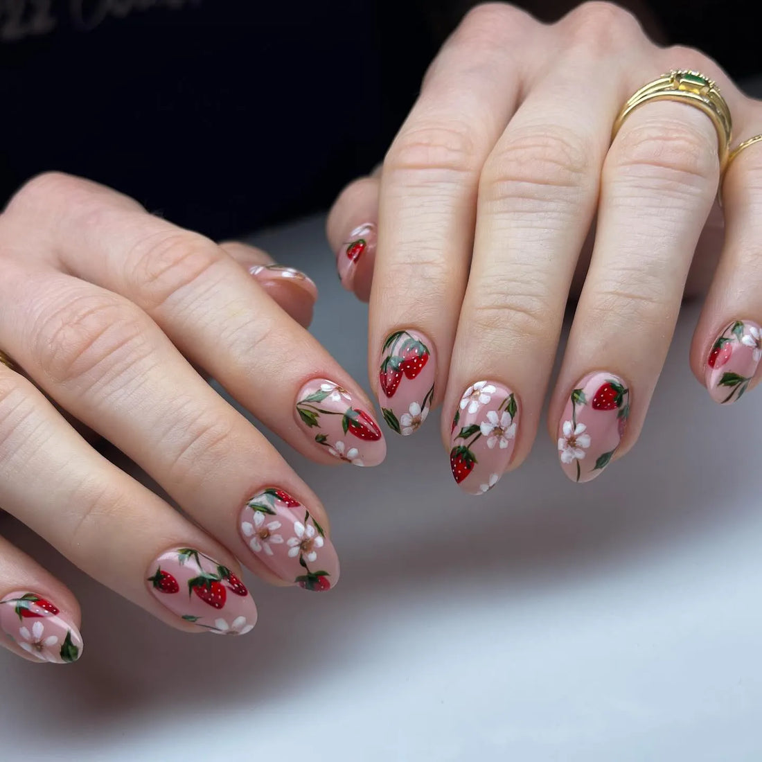 Handmade press-on nails with pink base, strawberry and white floral summer nail art.
