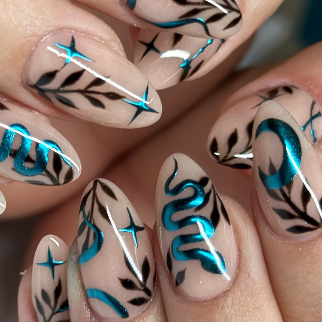 Handmade press-on nails with teal chrome snake, moon, black leaves, and celestial designs