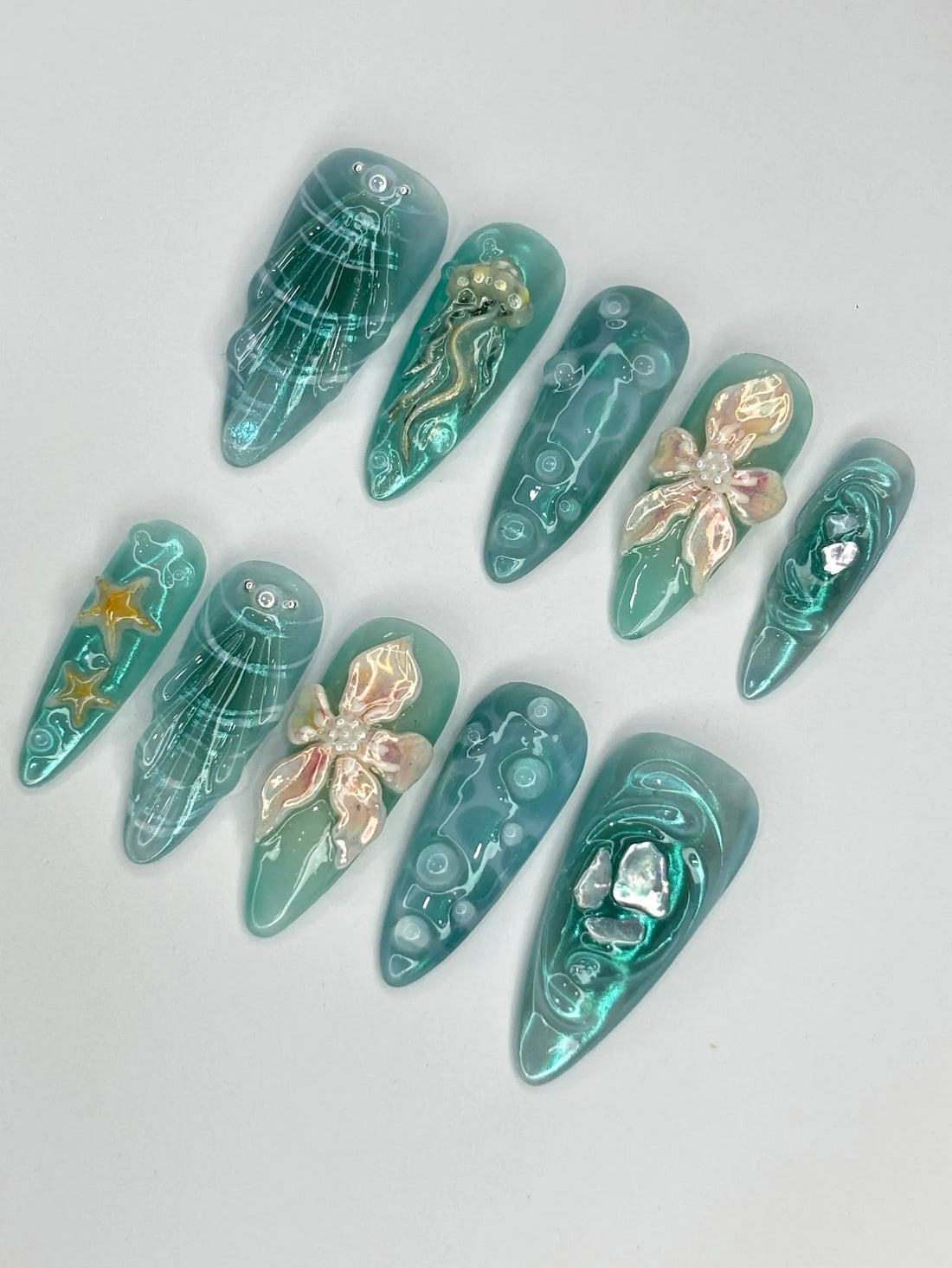 Handmade teal shimmer press-on nails with 3D ocean designs, jellyfish, starfish, and shells.
