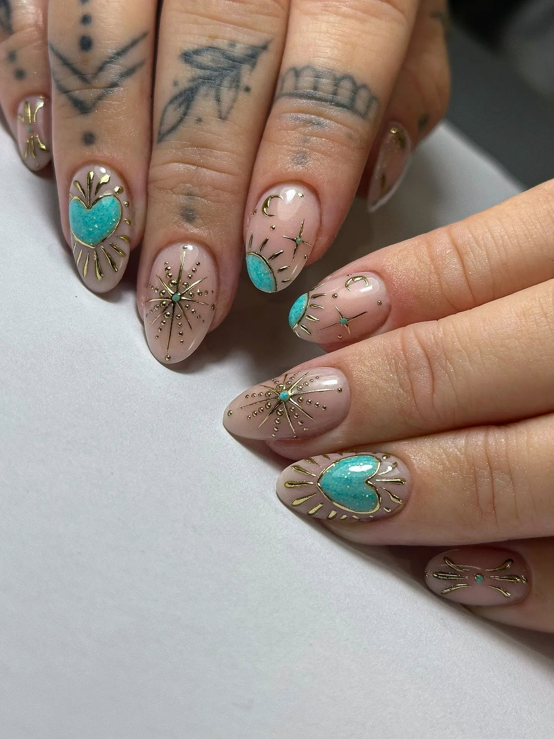 Handmade press-on nails with turquoise heart, celestial sunburst and gold detailing.