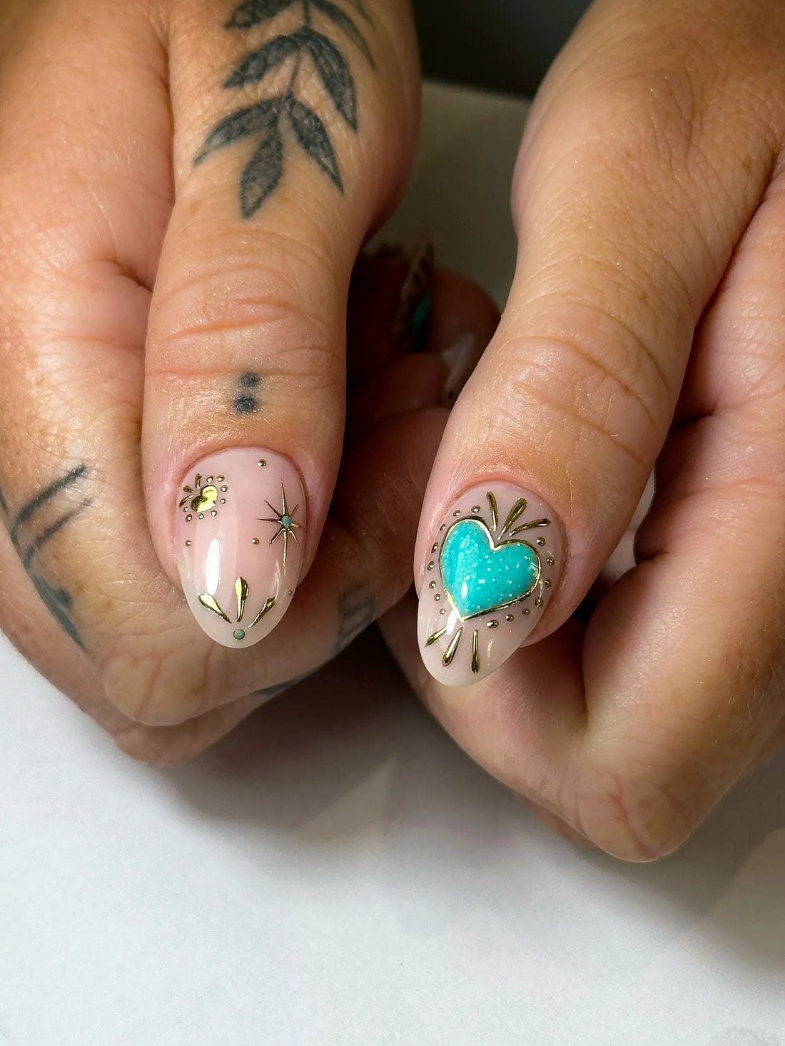 Handmade press-on nails with turquoise heart, celestial sunburst and gold detailing.