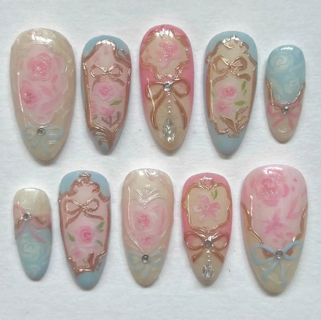 Handmade vintage press-on nails with pink and blue pastel floral and rose gold bow designs.