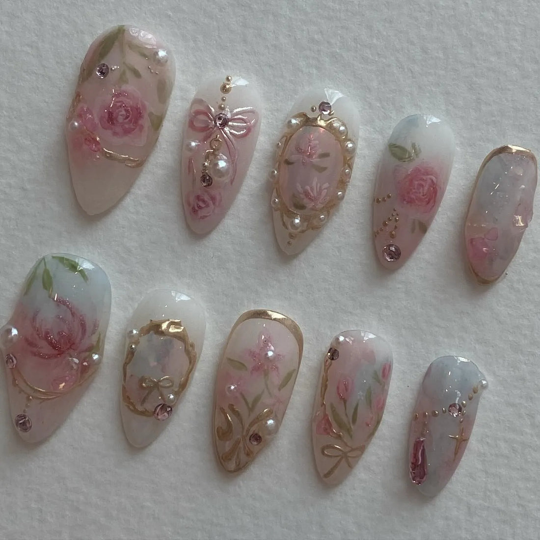 Handmade vintage press-on nails with pink rose, pearl, gold frame, and bow designs.
