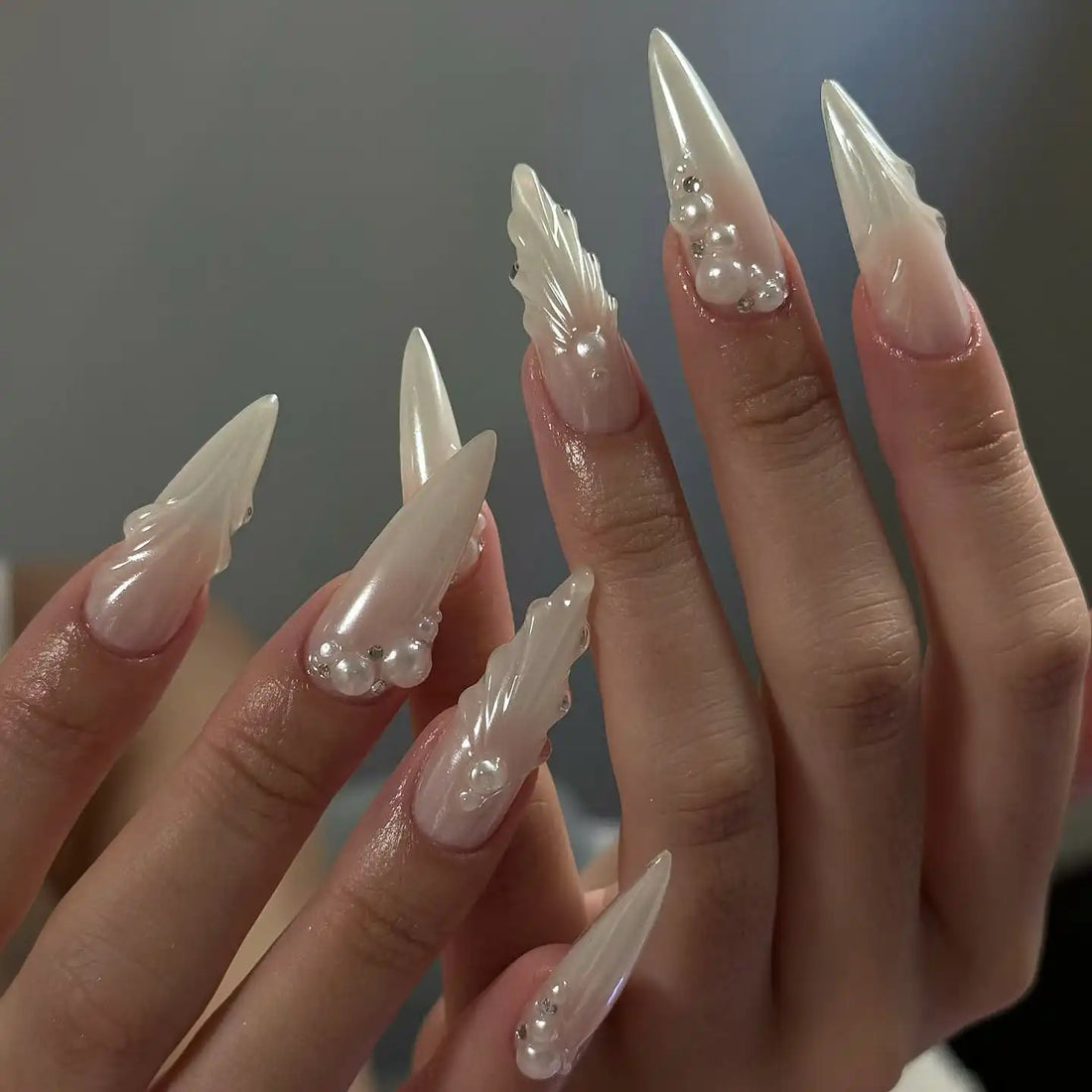 Handmade white press-on nails with elegant pearls and seashell 3D accents shown on hands