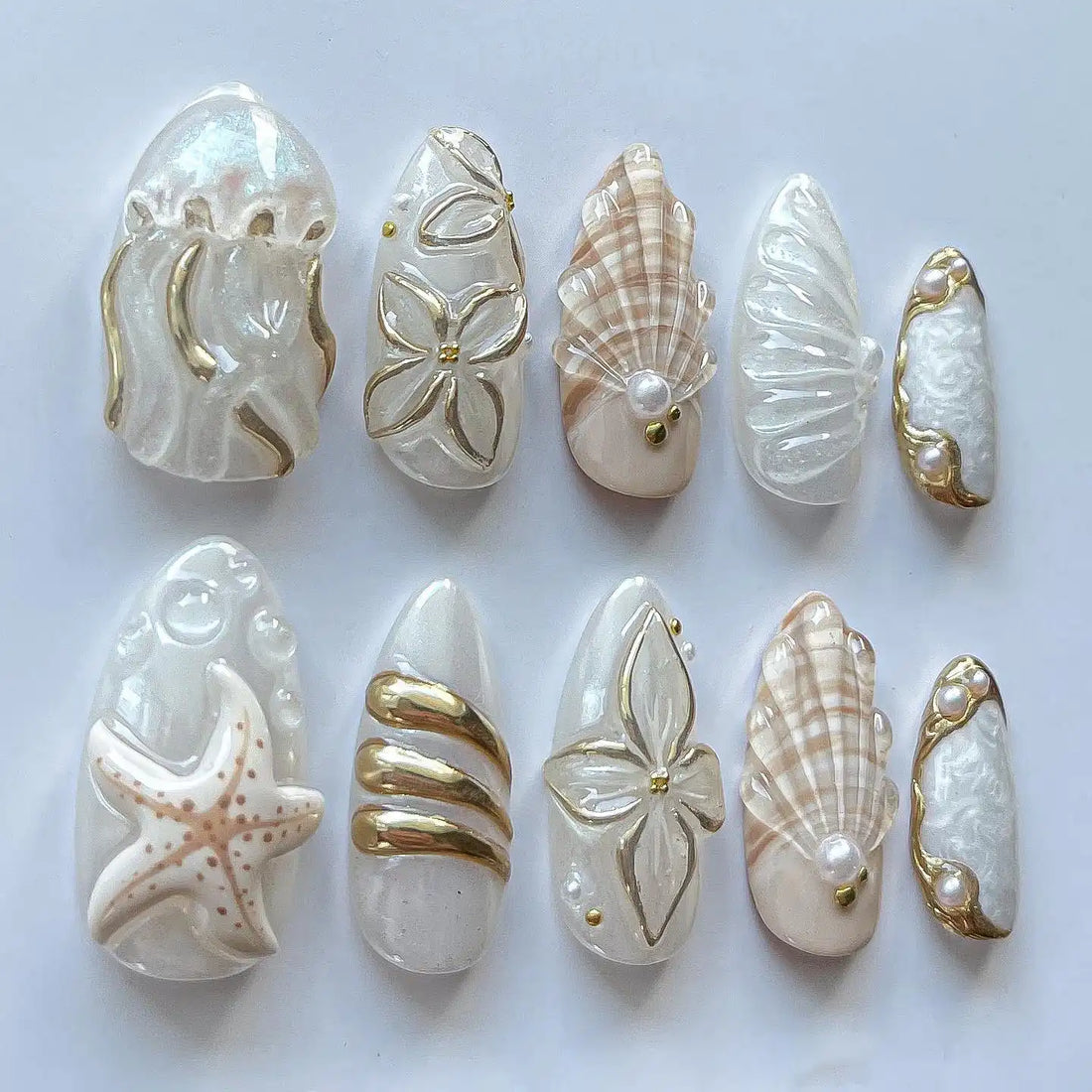 Handmade white and gold ocean-themed press-on nails featuring seashell, starfish, and jellyfish designs.