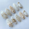 Handmade white and gold press-on nails with ocean-themed designs like seashells, starfish, and jellyfish.