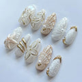 Handmade white and gold ocean-themed press-on nails with seashell, starfish, and jellyfish designs.